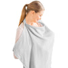 A woman wearing a light gray breathable muslin nursing cover with an adjustable neckline.