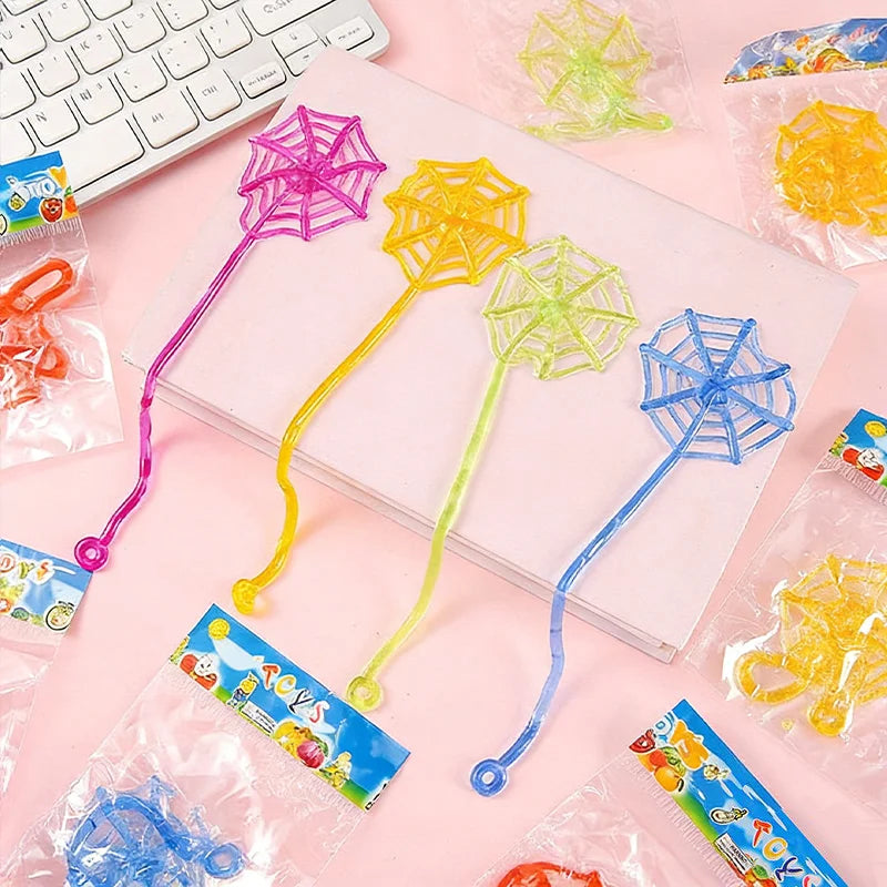 A collection of colorful stretchy sticky hands and spider web party favor toys in clear plastic bags.
