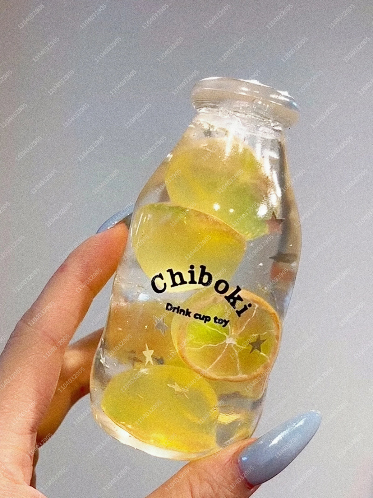 A hand holds a glass bottle filled with yellow fruit slices, serving as a drink cup toy.