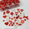 A collection of mixed red and clear acrylic bow and flower beads in a clear plastic container.