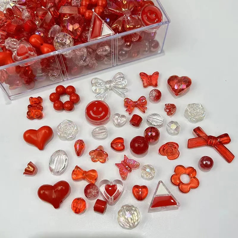 A collection of mixed red and clear acrylic bow and flower beads in a clear plastic container.