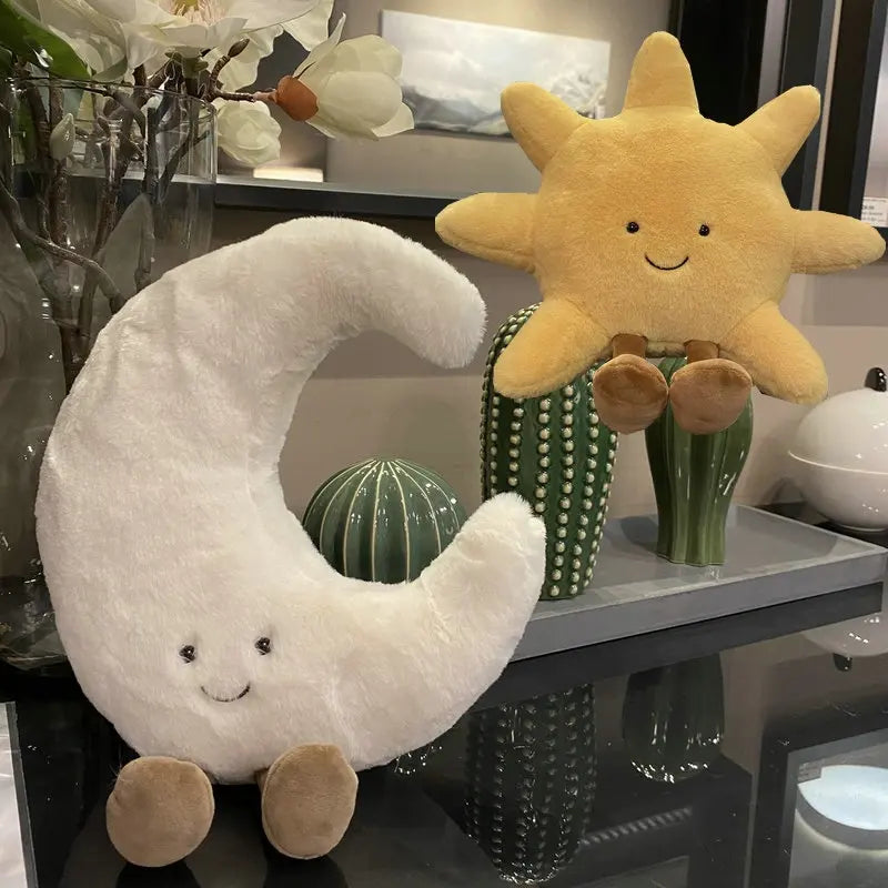 A set of plush toys featuring a yellow sun and a white crescent moon, displayed on a shelf.