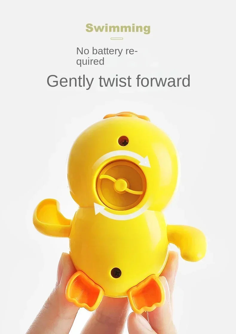 A yellow swimming duck bath toy is gently twisted forward, being held in a person's hand.