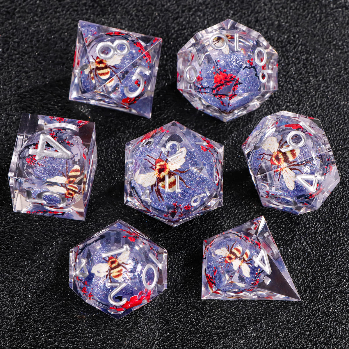 A set of liquid core polyhedral dice featuring blue and red glitter with bee designs on a dark background.