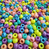 A close-up view of a large pile of multicolor pony beads in various shades of pink, purple, yellow, and blue.
