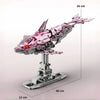 A pink and silver mechanical dragonfly model kit displayed on a stand with dimensions 26 cm by 40 cm.