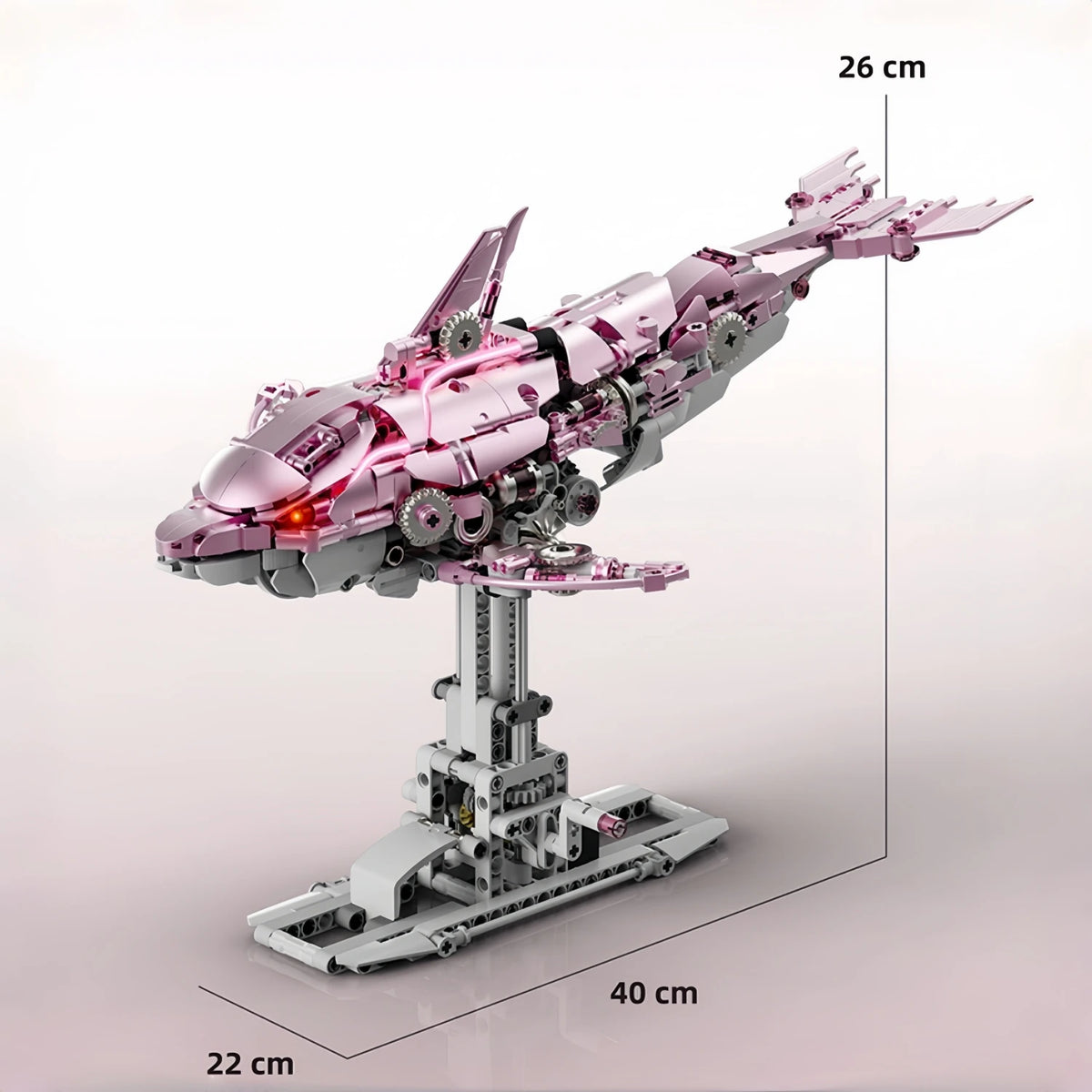 A pink and silver mechanical dragonfly model kit displayed on a stand with dimensions 26 cm by 40 cm.