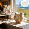 A white ceramic candle mold shaped like a horse with Celtic knot detailing, displayed on a shelf next to a window.