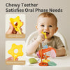A baby is using a yellow chewy teether toy while sitting in a white bowl, with other teethers nearby.