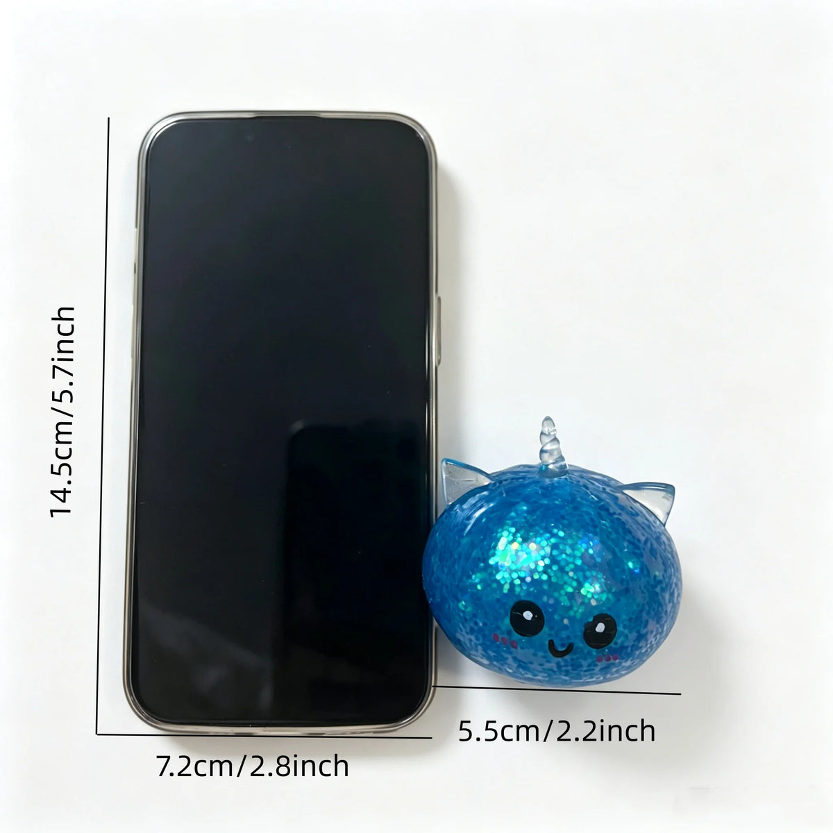 A black smartphone is shown next to a blue glittery unicorn dumpling squishy stress ball.