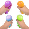 Hands holding various colored slow rising squishy stress balls including purple, orange, and green