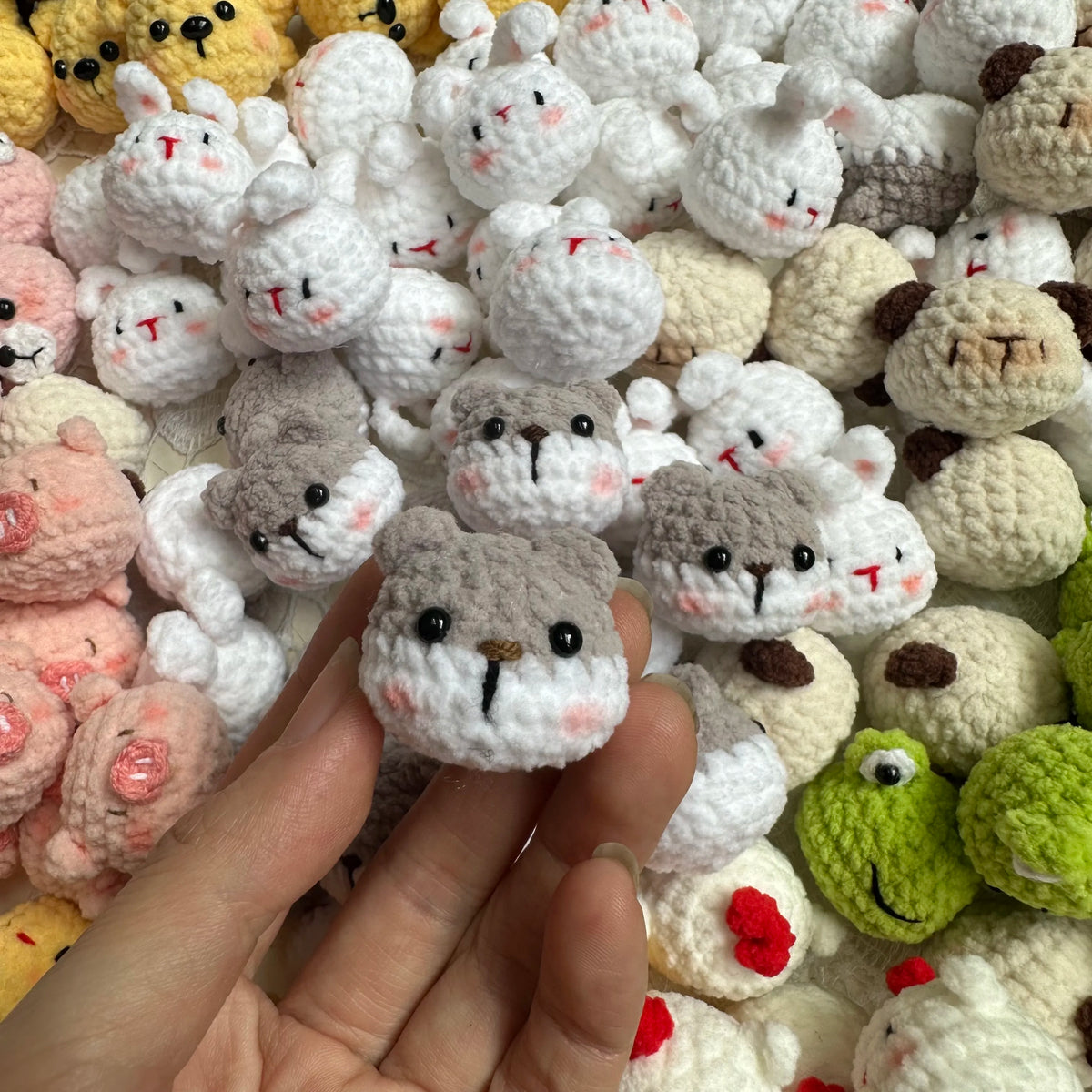 A close-up of various handcrafted crochet animal keychains including rabbits, chicks, cats, and dogs.