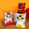 A solar-powered shaking head lion figurine in red and white sits on a clear display box.