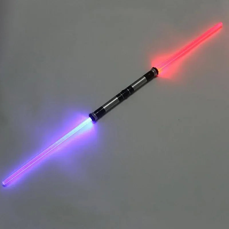 A toy lightsaber with a clear plastic blade emitting pink and blue laser light.