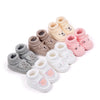 A collection of handmade knitted baby booties in various pastel shades including pink, beige, and gray.