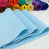 A stack of light blue felt fabric sheets rolled and laid out next to various colored felt rolls.