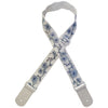 A beige woven guitar strap with blue floral embroidery and leather accents, shown in an X-shape.