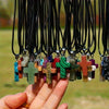 A hand holds a collection of natural stone cross pendants with various colors and textures.