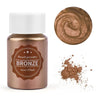 A glass jar of bronze pearl powder with a circular swatch and scattered powder on a white background.