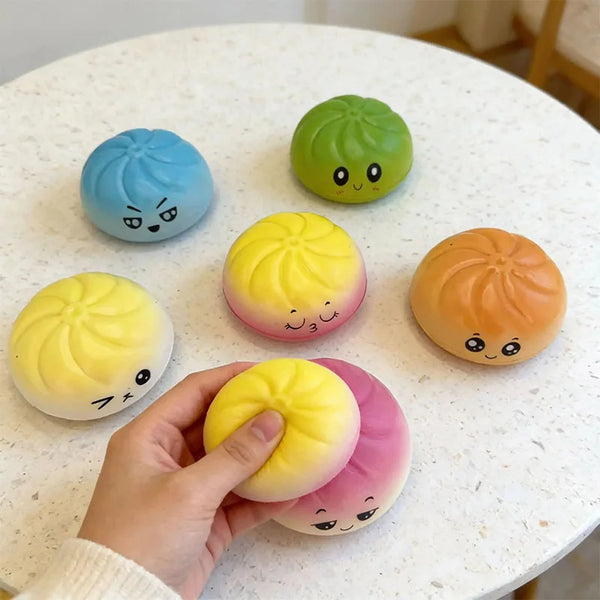 A hand holds a yellow squishy stress relief toy next to several colorful, squishy, egg-shaped toys.