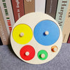 A wooden shape and color sorter puzzle with five colored circles on a light background.