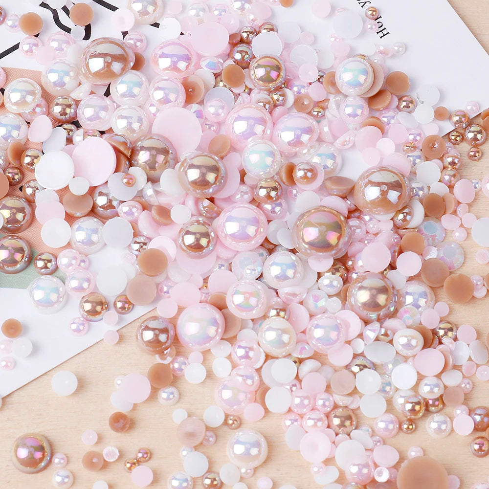 A pile of mixed resin rhinestone pearls with an AB finish in various shades of pink and nude for crafts and nail art.
