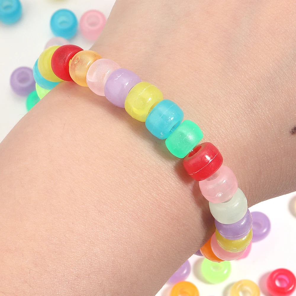 A wrist is shown wearing a string of colorful pony beads for DIY jewelry making.