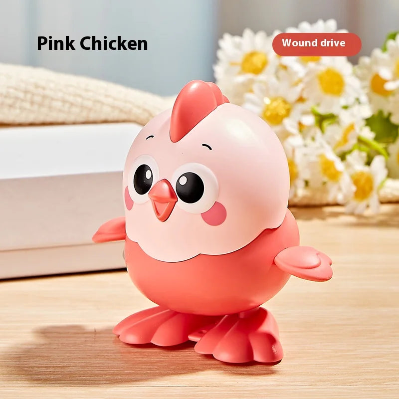 A pink cartoon chicken wind-up toy sitting on a wooden surface with white and yellow flowers in the background.