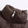 A close-up of a dark brown padded down vest with a silver zipper.
