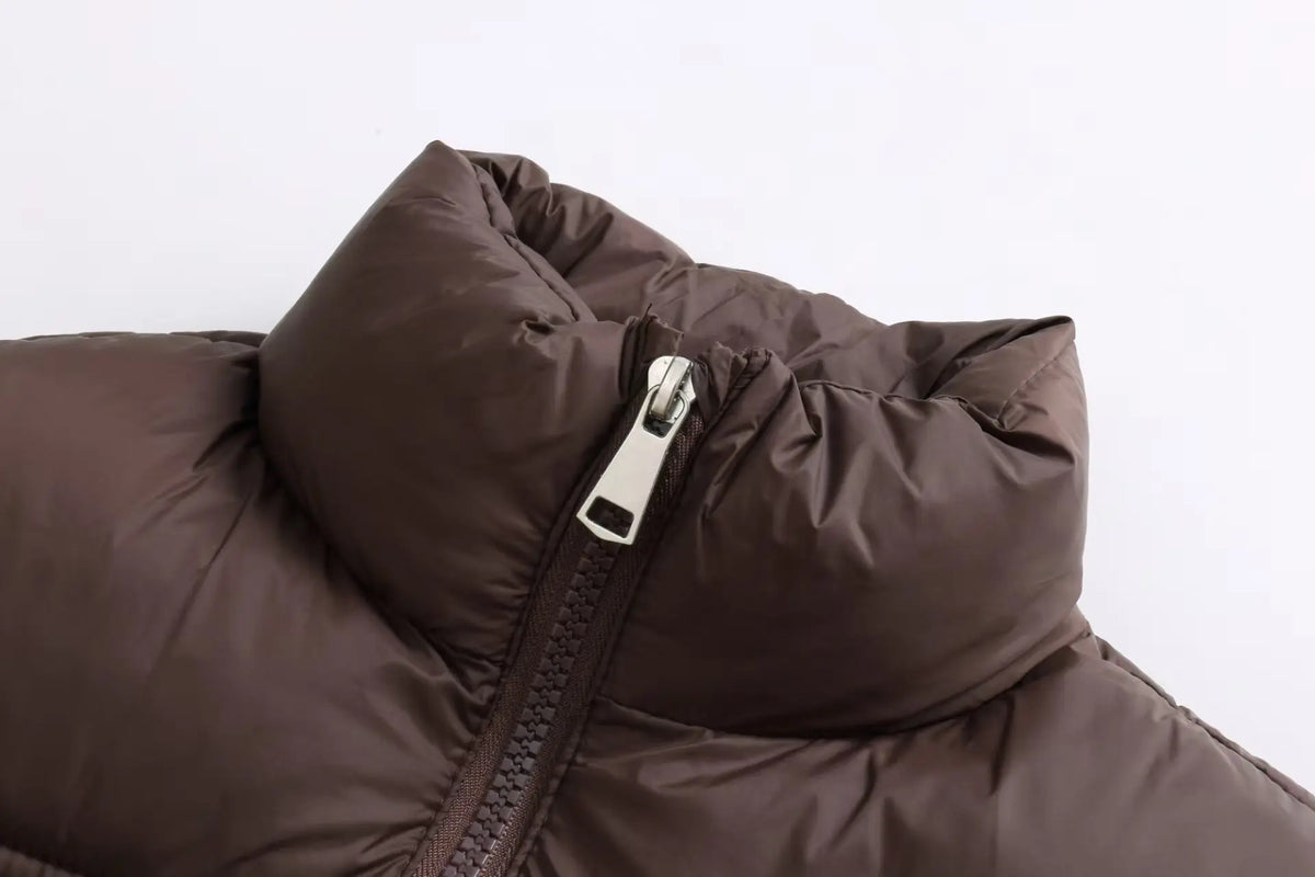 A close-up of a dark brown padded down vest with a silver zipper.