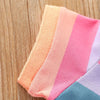A striped pink and orange fabric garment laid on a wooden surface.