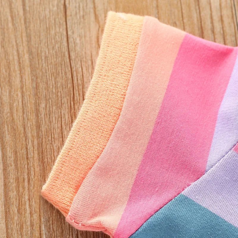 A striped pink and orange fabric garment laid on a wooden surface.