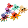 A collection of colorful 3D printed articulated octopus fridge magnets in various shades of pink, blue, green, and yellow.