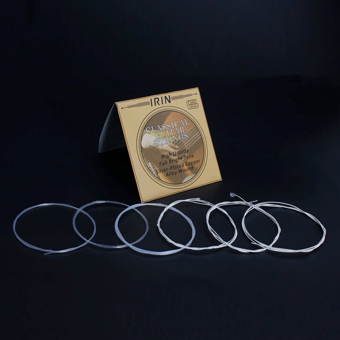 A package of classical guitar strings with a silver-plated core is displayed on a dark surface.