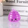 A small, translucent purple glitter squishy stress ball shaped like a smiling face resting on a reflective surface.