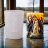 A lit candle in a glass holder featuring a Halloween witch portrait design.
