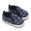 A pair of navy blue baby first walker sneakers featuring a white dinosaur print.