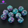 A set of ten glitter polyhedral dice in various shades of blue and purple scattered on a dark surface.