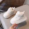 A hand holds a pair of white toddler winter snow boots with quilted fabric and soft sole.
