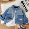 A blue and white striped denim jacket laid flat on a white cloth next to a stack of books.