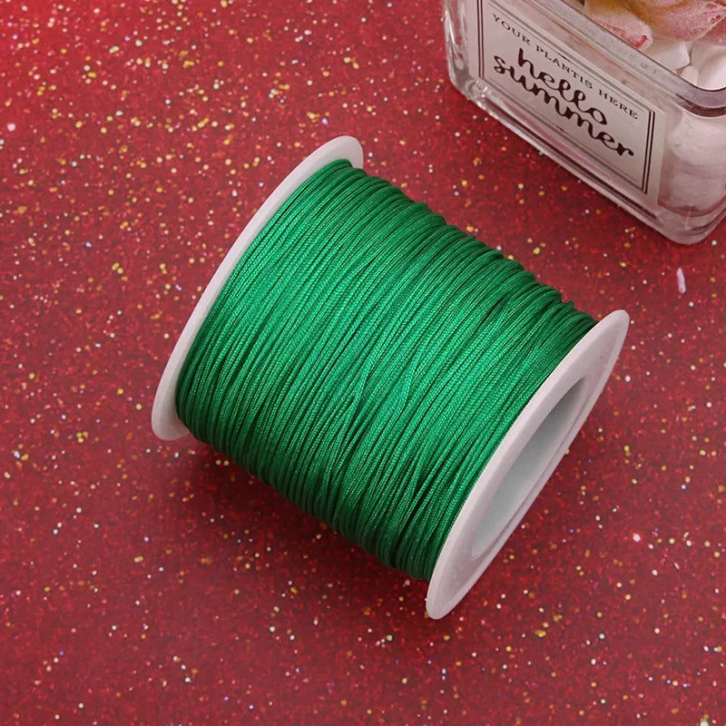 A spool of bright green nylon knotting cord for jewelry making resting on a red, glittery surface.