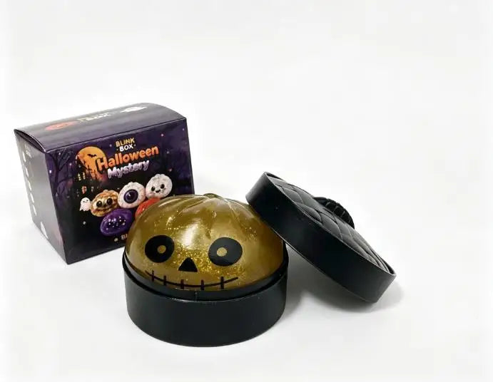 A black box and a golden pumpkin-shaped squishy stress relief toy are shown on a white background.