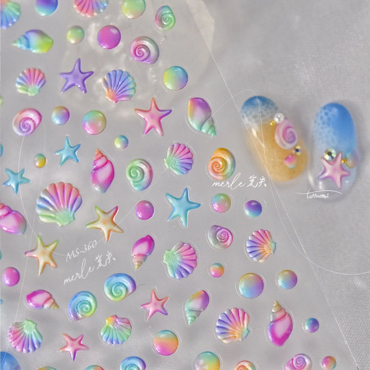 Collection of iridescent nail art stickers featuring gold shells and starfish on a clear sheet.