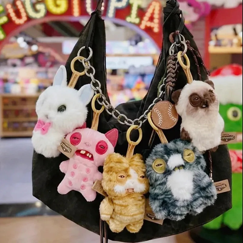 A collection of cute plush keychain charms featuring various animals like rabbits, pink pigs, and cats displayed on a black f
