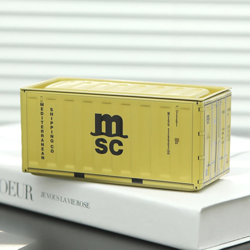 A yellow miniature industrial iron storage box with an openable lid resting on a white book.