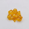 A collection of ten yellow acrylic polyhedral dice scattered on a white surface.