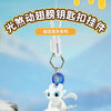 A white Toothless Dragon keychain with movable wings and glowing eyes is displayed on a snowy rock.