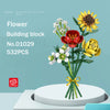 A bouquet of colorful flowers, including red, yellow, and white blooms, is displayed on a white circular base.