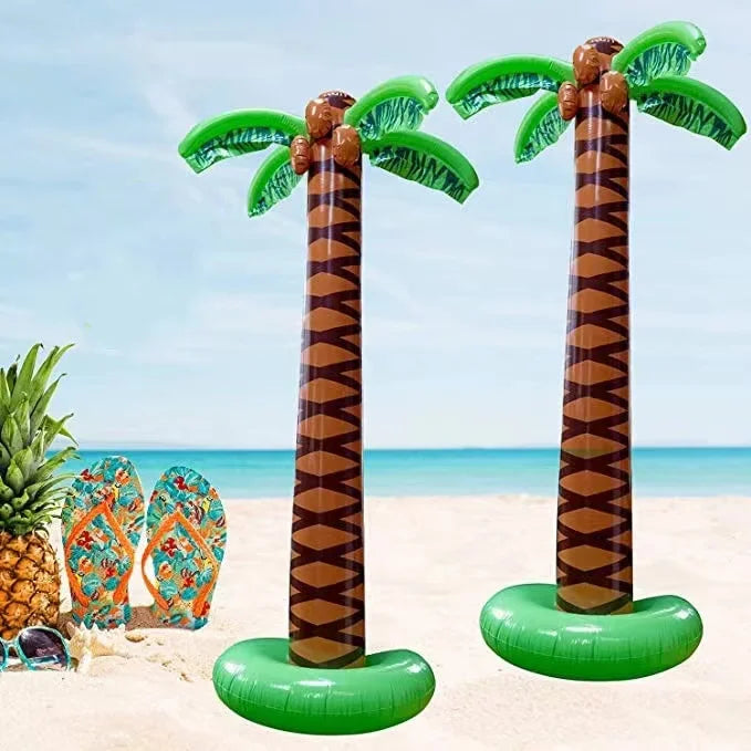Two oversized inflatable palm trees with green fronds and brown trunks on a sandy beach.