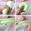 A hand squeezes a bright lime green dumpling-shaped squishy stress ball with a mini steamer.